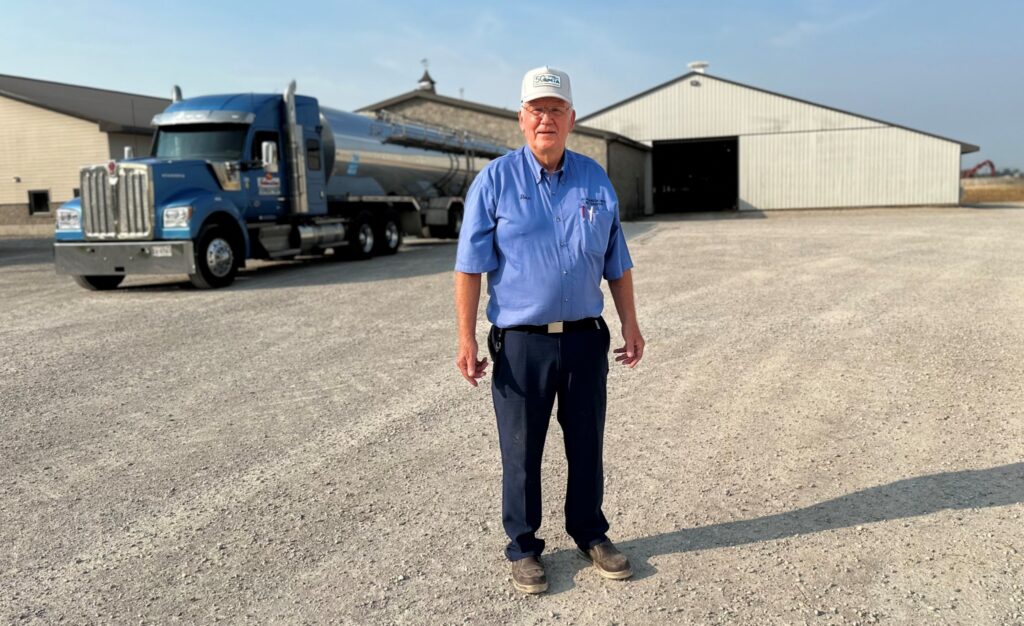 A truck driver in front of his truck at a farm