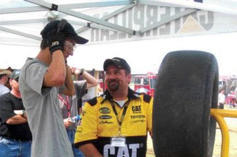 CAT CONTEST: A contestant (left) is assisted by Dave Dyer, product support manager at Toromont's Concord, Ont.-based truck facility, before trying his luck at Caterpillar's pit crew tool challenge. Photo by Adam Ledlow