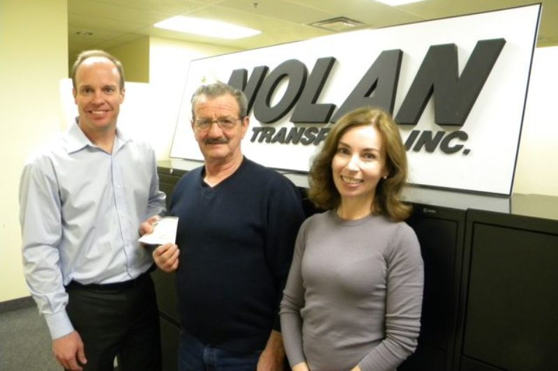 Nolan Transport vp Jim Peacock (left) presents a cheque to former owner/operator Dave Monroe (middle), along with co-owner Kelly Nolan.