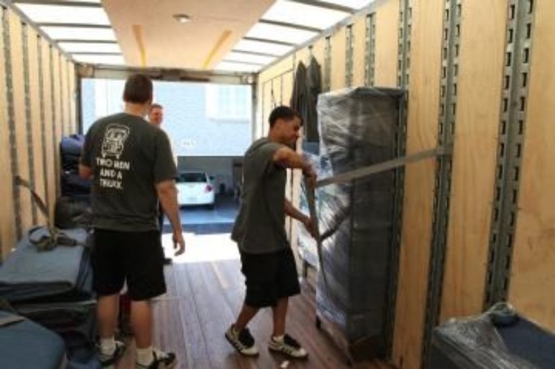 Movers with Two Men and a Truck secure a load of household goods.