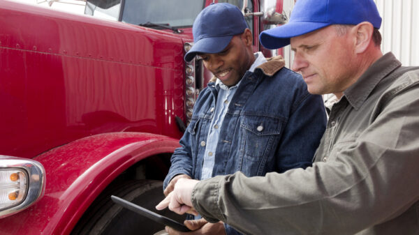 Men standing in front of a truck looking at a tablet