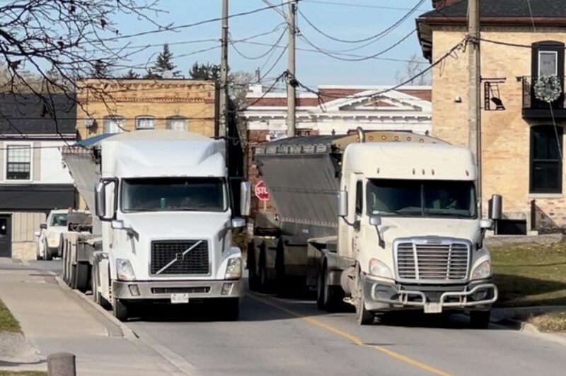 Two trucks on a narrow Ayr road.