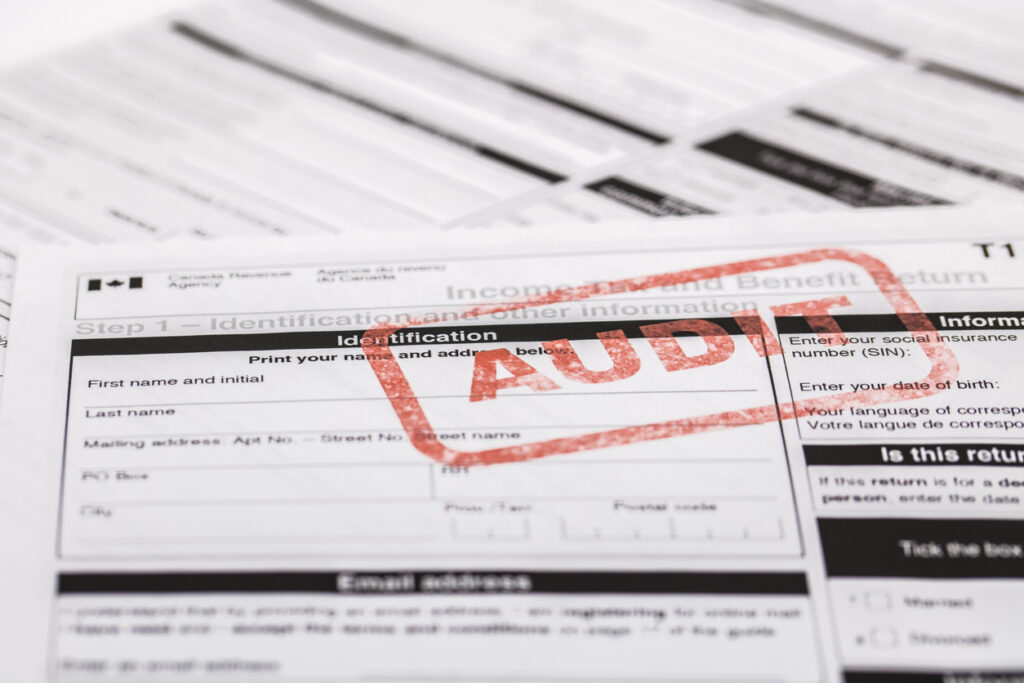 A stock photo of the Canadian T1 General Tax forms. Showing a red ink stamp with the word "AUDIT"