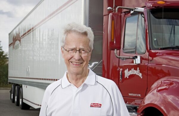 Doug Smith, founder of Manitoulin Transport, in front of it's branded truck and trailer