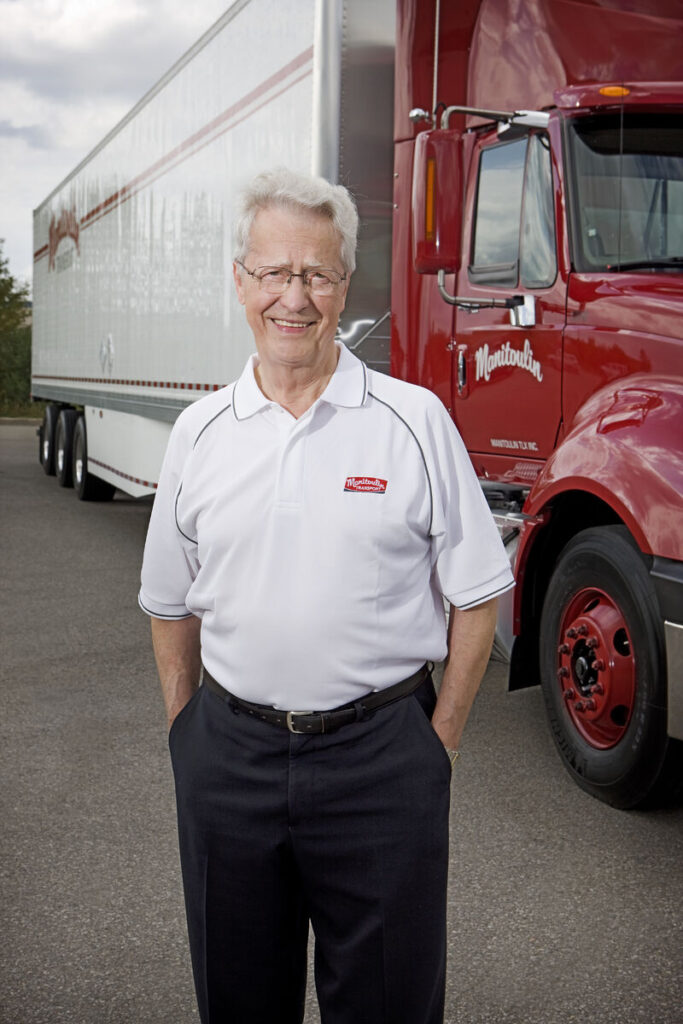 Doug Smith, founder of Manitoulin Transport, in front of it's branded truck and trailer